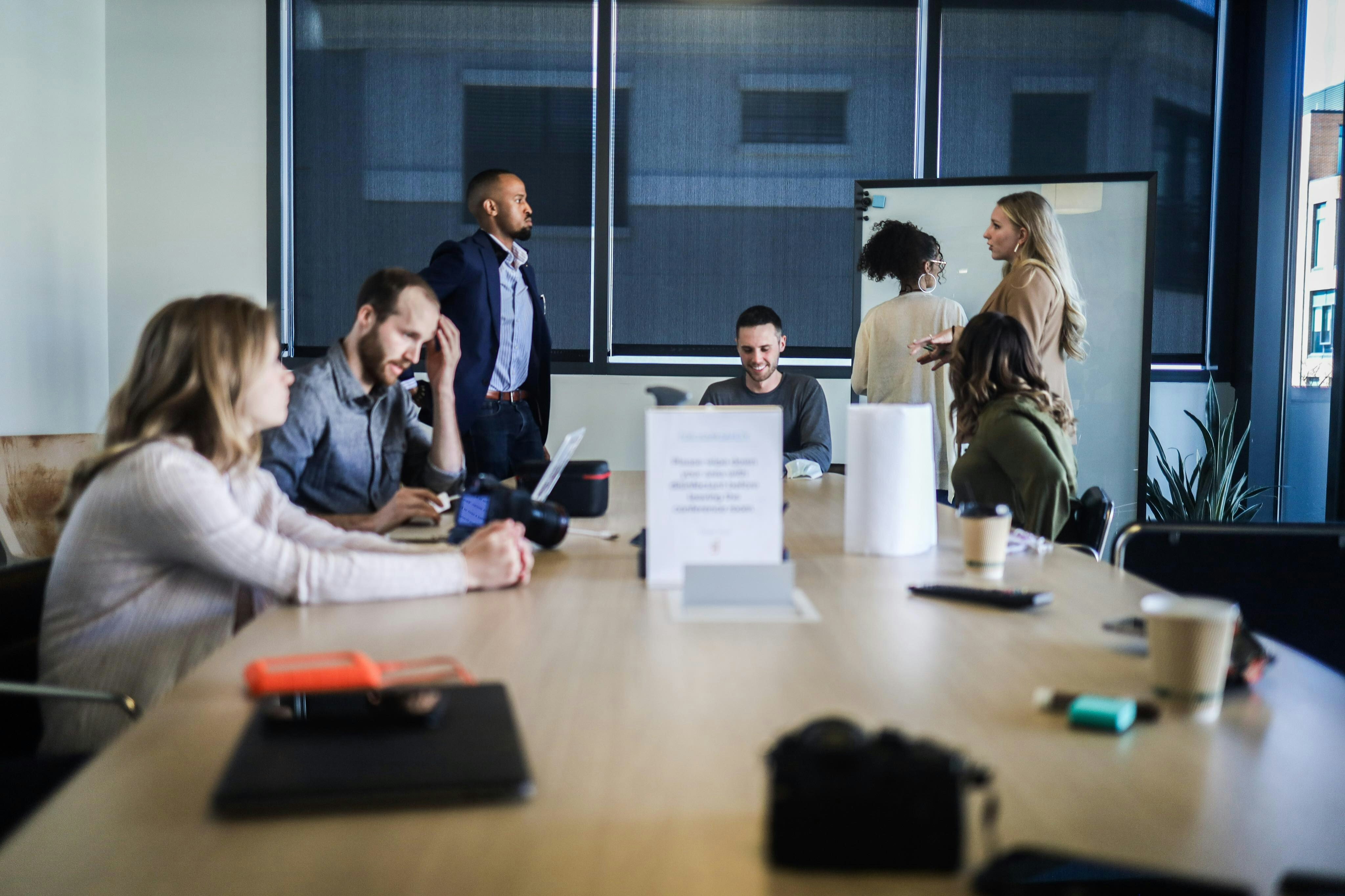 A team or group of employees moving forward energetically while a leader or decision-maker appears disconnected or observing from a distance.