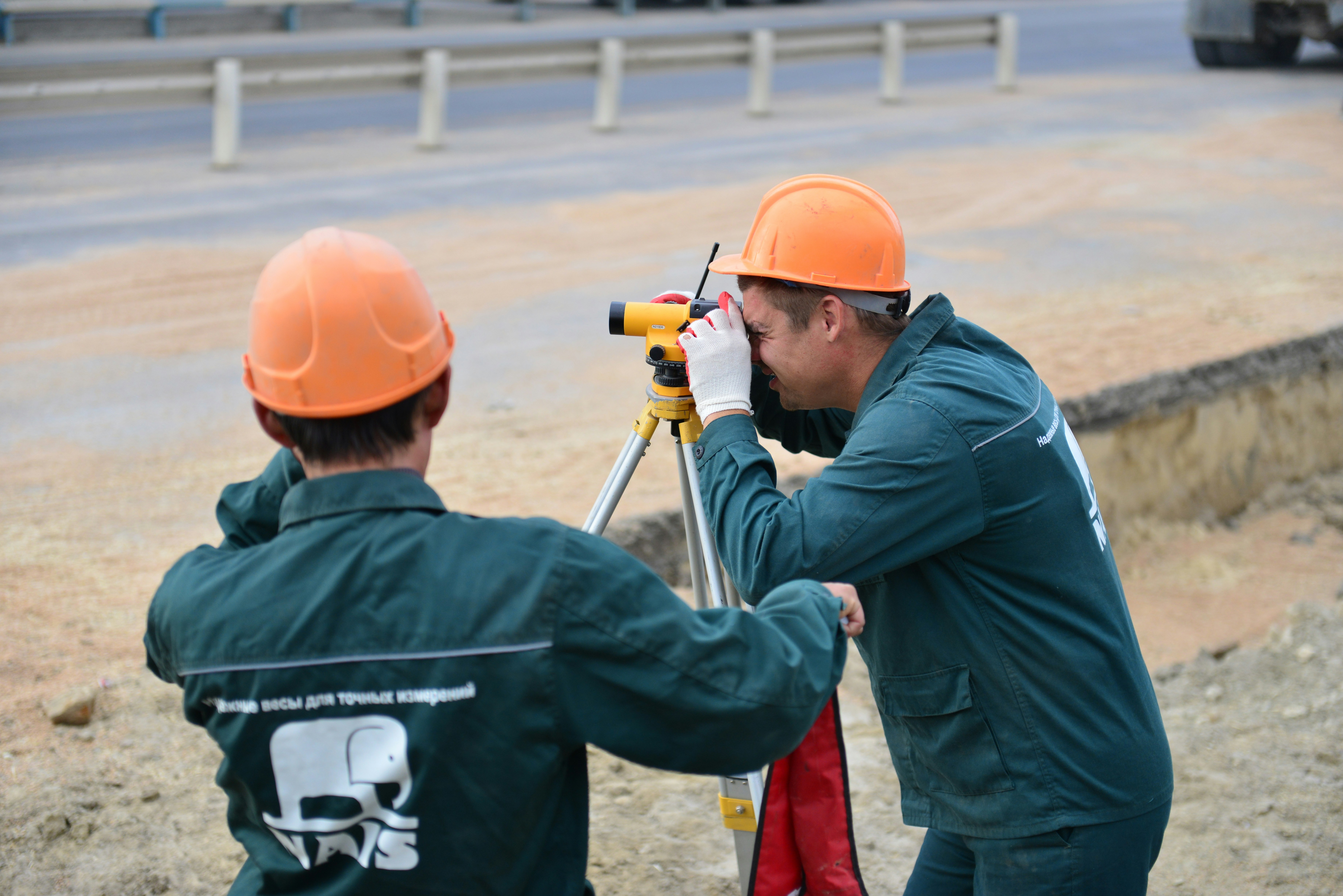 Two men looking through equipment working near a road