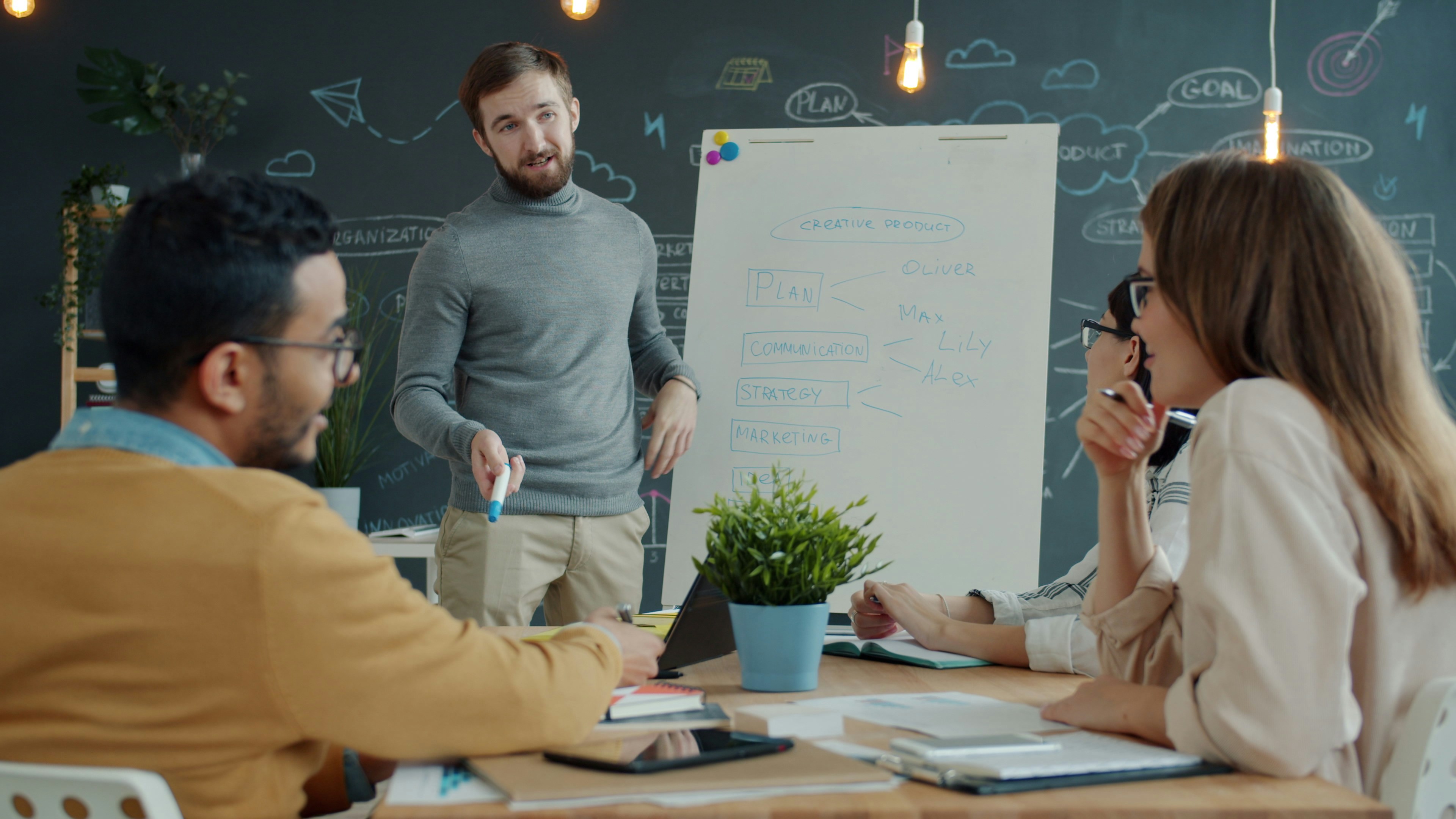 a leader presenting data to a team — but with visible engagement (discussion, reaction) avoid staged “presentation” shots — aim for something candid and real
