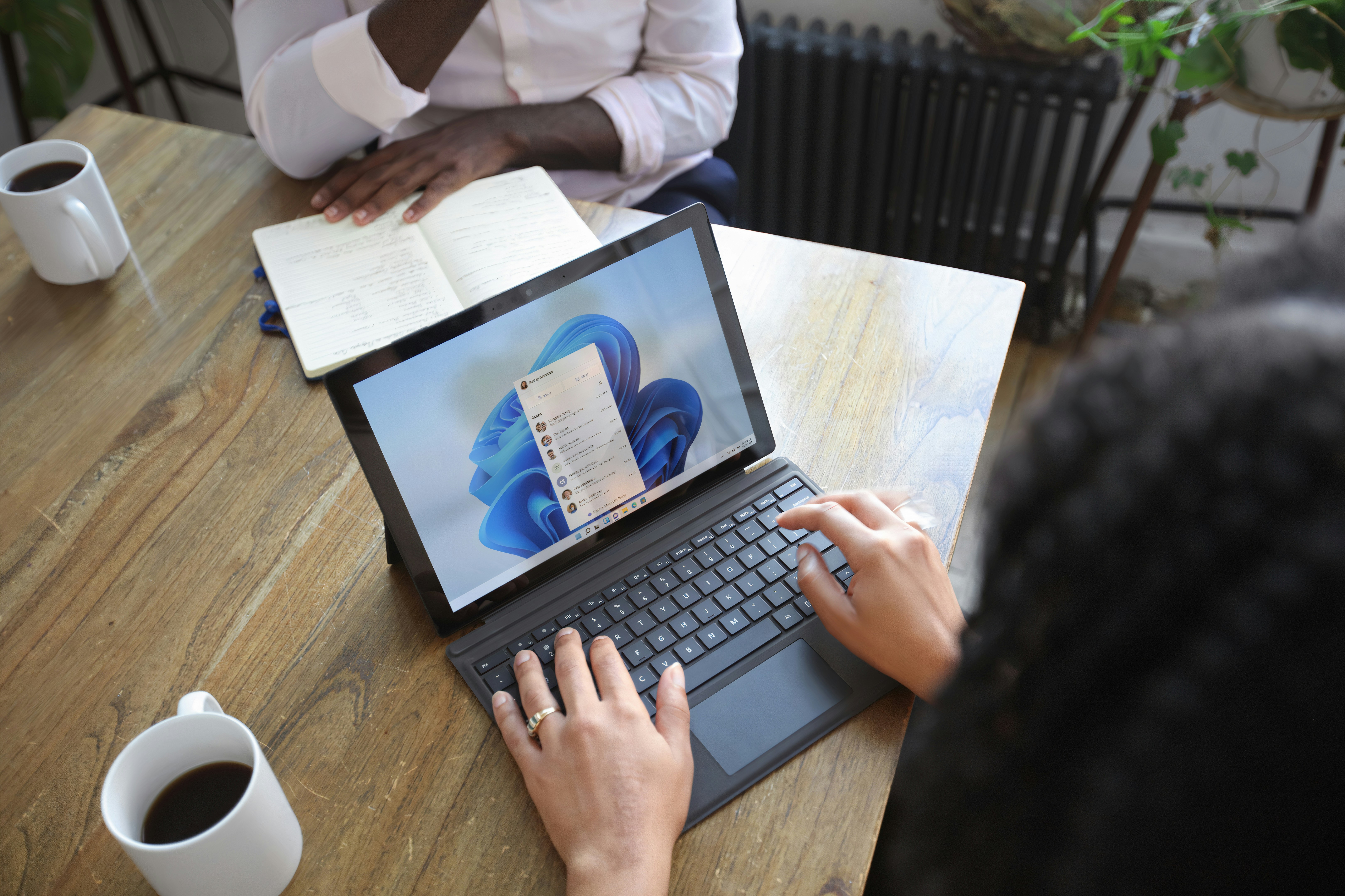 A candid image of a leader reviewing feedback on a tablet or laptop while employees collaborate in the background — slightly out of focus.